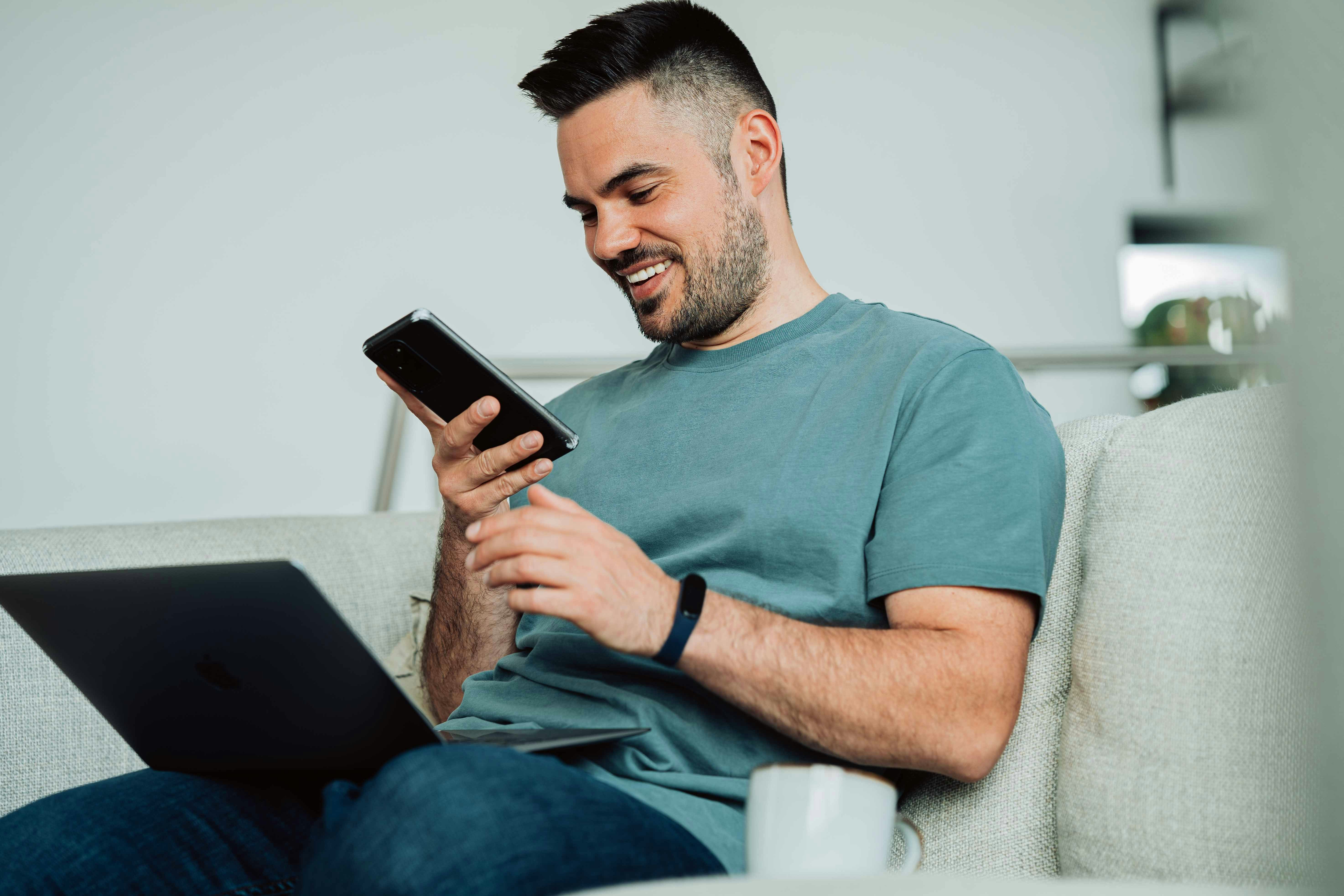 A man is smiling while looking at his phone